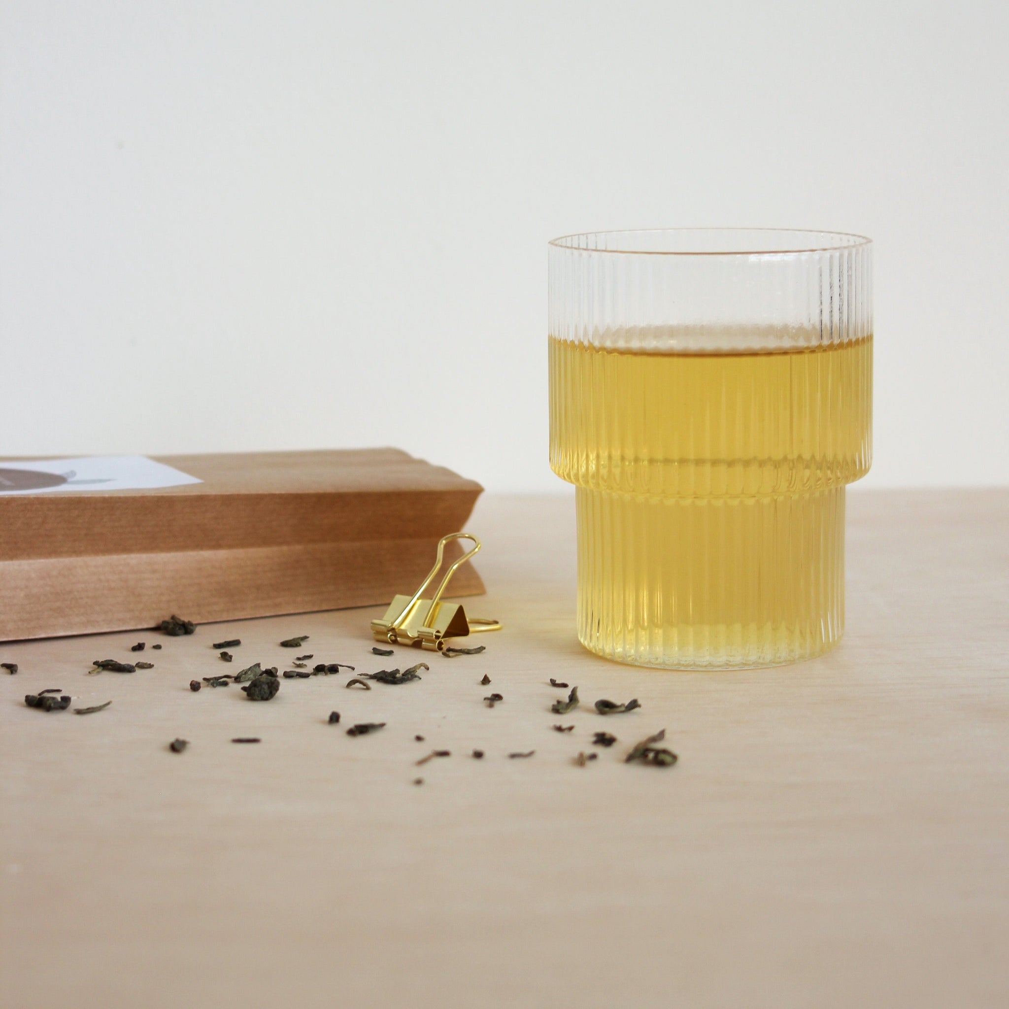 Jacob Hooij groene thee in ribbel glas met op de voorgrond losse thee en op de achtergrond een theezakje